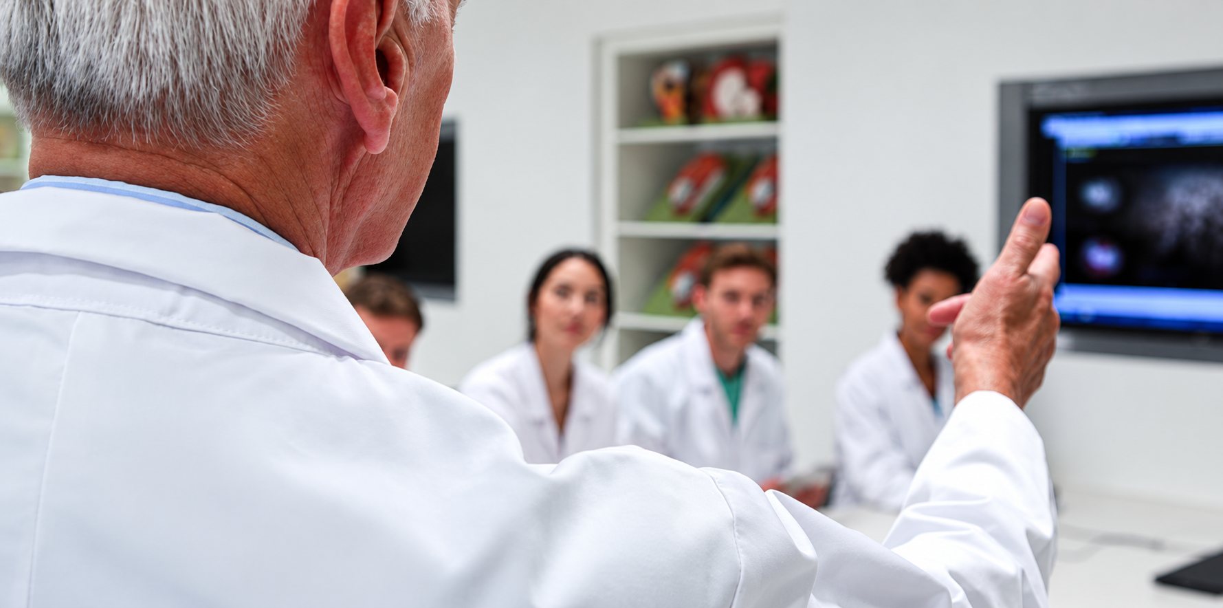 Médecin en blouse blanche expliquant une radiographie à un groupe d’étudiants.