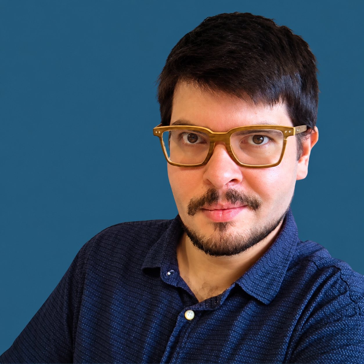 Portrait de Rémi Toledo, conseiller formation, devant un fond bleu uni.