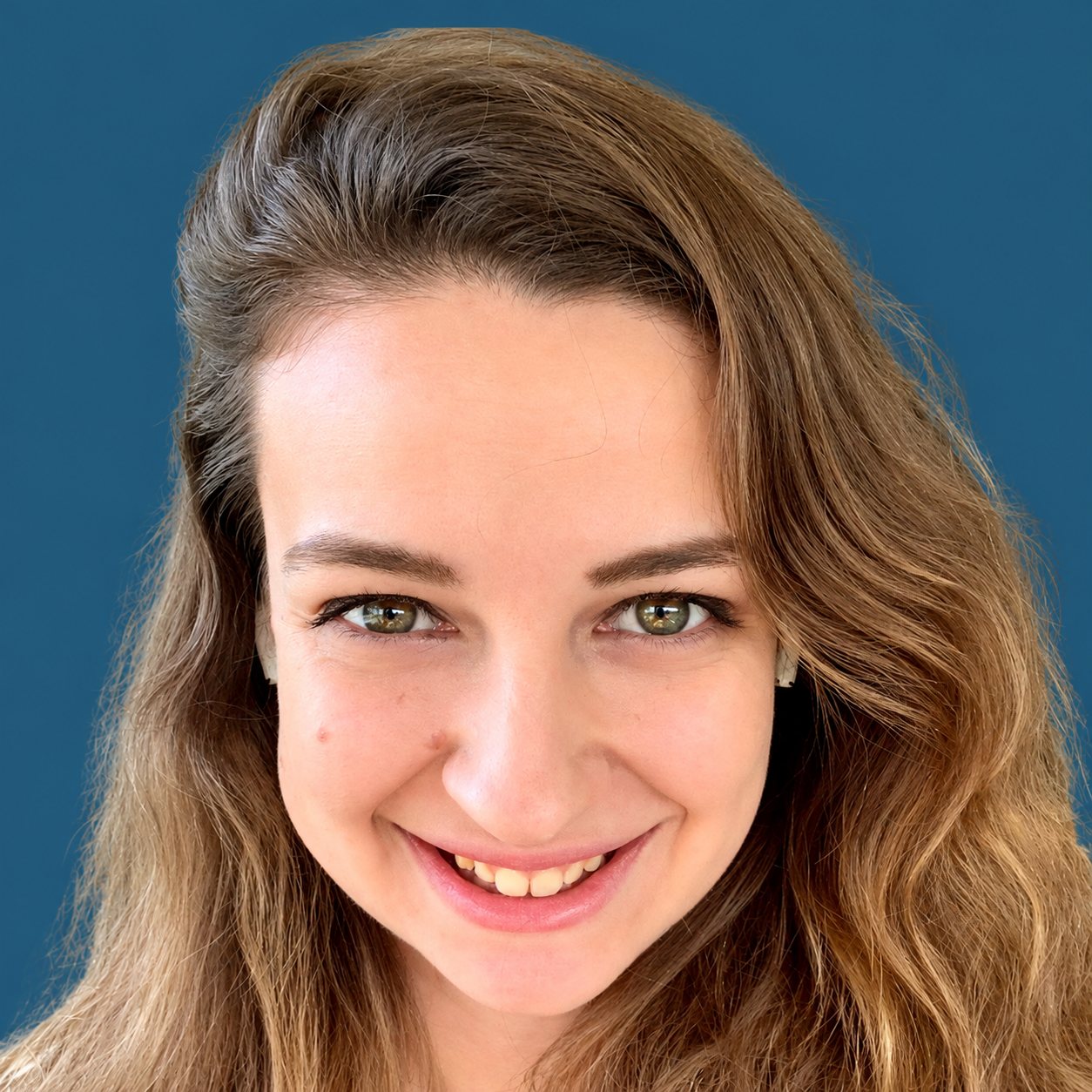 Portrait de Julie Menudier, chargée pédagogique et formatrice, devant un fond bleu uni.